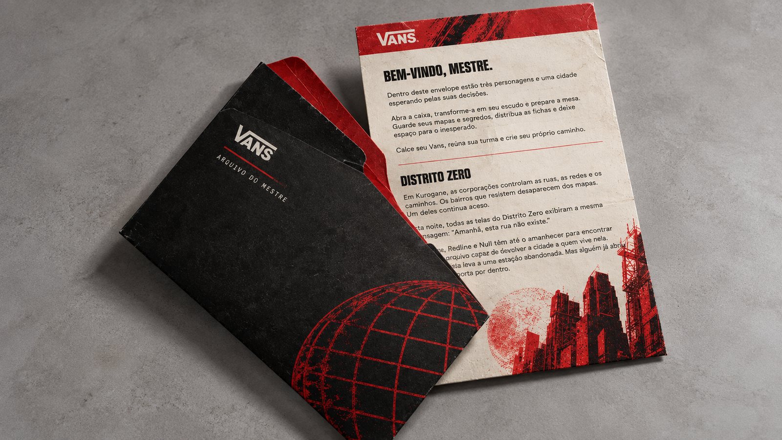 Envelope preto Arquivo do mestre, com o globo em vermelho, e a carta Bem-vindo, mestre, com o texto do Distrito Zero e prédios em vermelho e preto